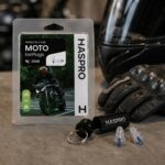 HASPRO Moto ausų kištukai šalia motociklininko pirštinių ir šalmo